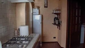 A kitchen with a gas stove, a refrigerator, and tiled flooring. - B&B Rivellini (Tropea)