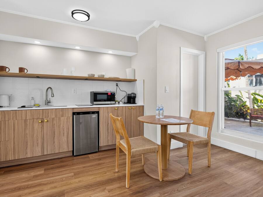 Une cuisine moderne avec des meubles en bois, un lave-vaisselle et un four à micro-ondes. On y trouve un coin repas avec deux chaises et une table, ainsi qu’une fenêtre donnant sur l’extérieur.