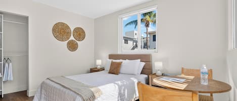 A hotel room with a bed, bedside tables, a window with a view, a round wooden table, and a chair.