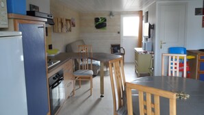 A compact kitchen with wooden cabinets, a refrigerator, a stove, and a dining area with chairs. - Rest Sea Sun comfort at 600m beach (la plaine sur mer Tharon plage)