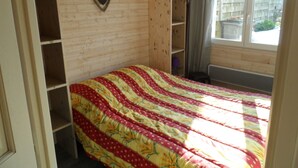 A bedroom with a bed, wooden shelving, a window, and a radiator. - Rest Sea Sun comfort at 600m beach (la plaine sur mer Tharon plage)