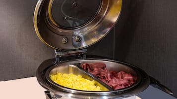 Un electrodoméstico de cocina con pantalla digital, que contiene huevos revueltos y carne en rodajas.