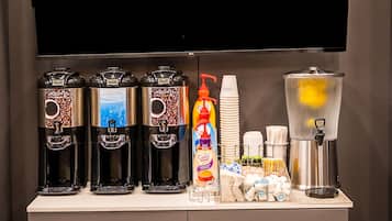 A beverage station with three coffee makers, a water dispenser, and various cups and utensils.