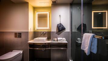 Un baño moderno con cabina de ducha de vidrio, tocador con espejo y un inodoro.