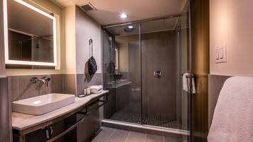 A modern bathroom with a glass-enclosed shower, a large mirror, and a vanity with a sink.