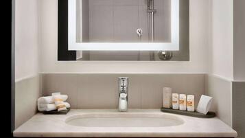 A bathroom with a large mirror, a sink, and a shower.