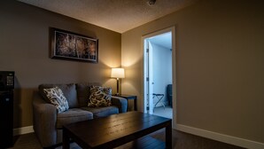 Uma sala de estar com sofá, mesa de centro, abajur e um quadro na parede.