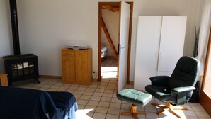 A room with a bed, a wooden cabinet, a green cushioned bench, a wardrobe, and a black heater.