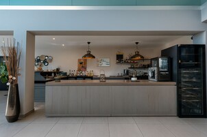Una cocina moderna con una isla central, iluminación colgante y un refrigerador negro.