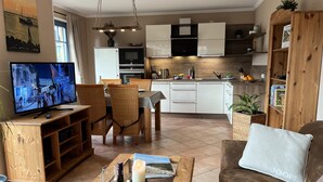 Een moderne woonkamer met een televisie, eethoek en keuken.
