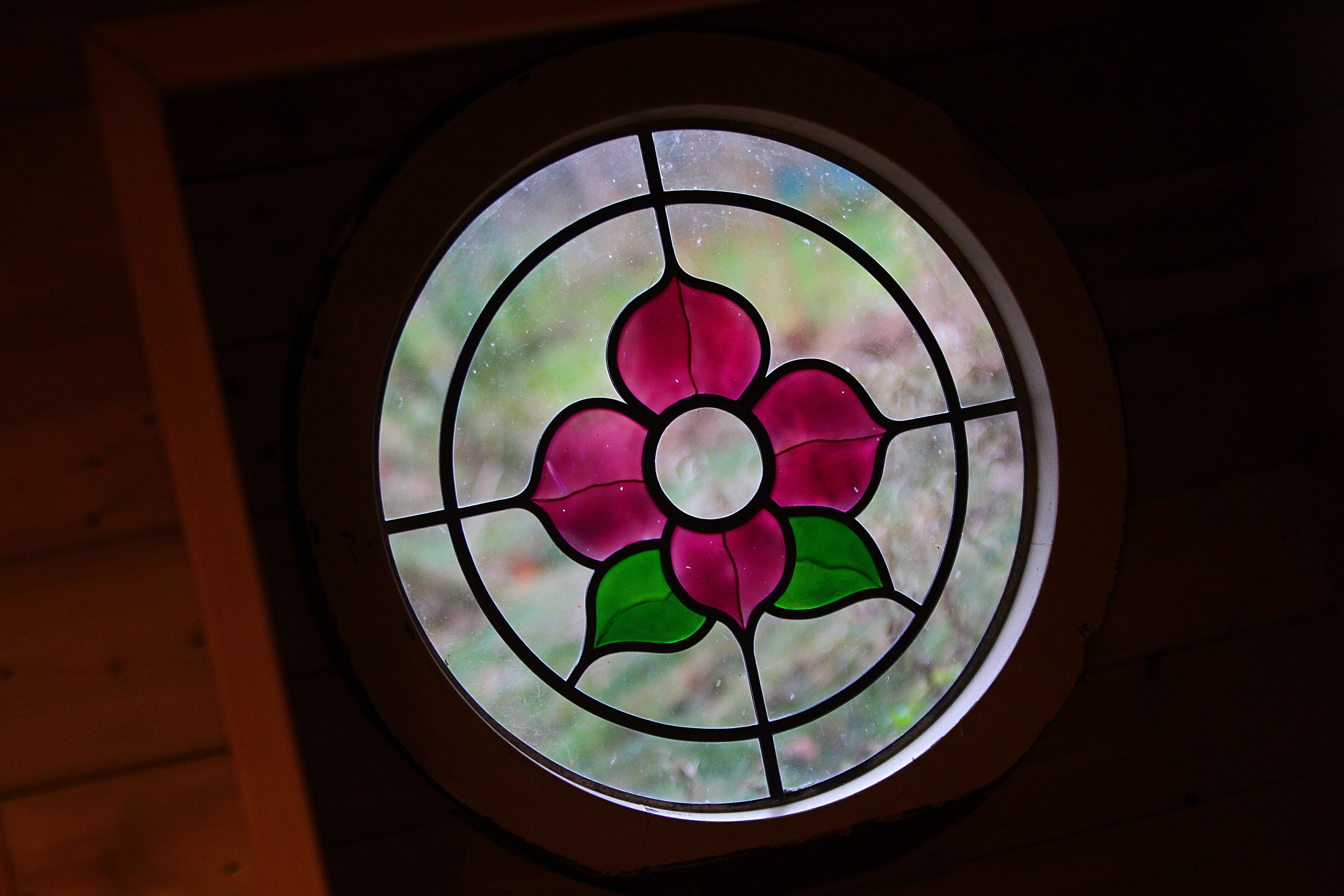 A circular stained glass window with a floral design.