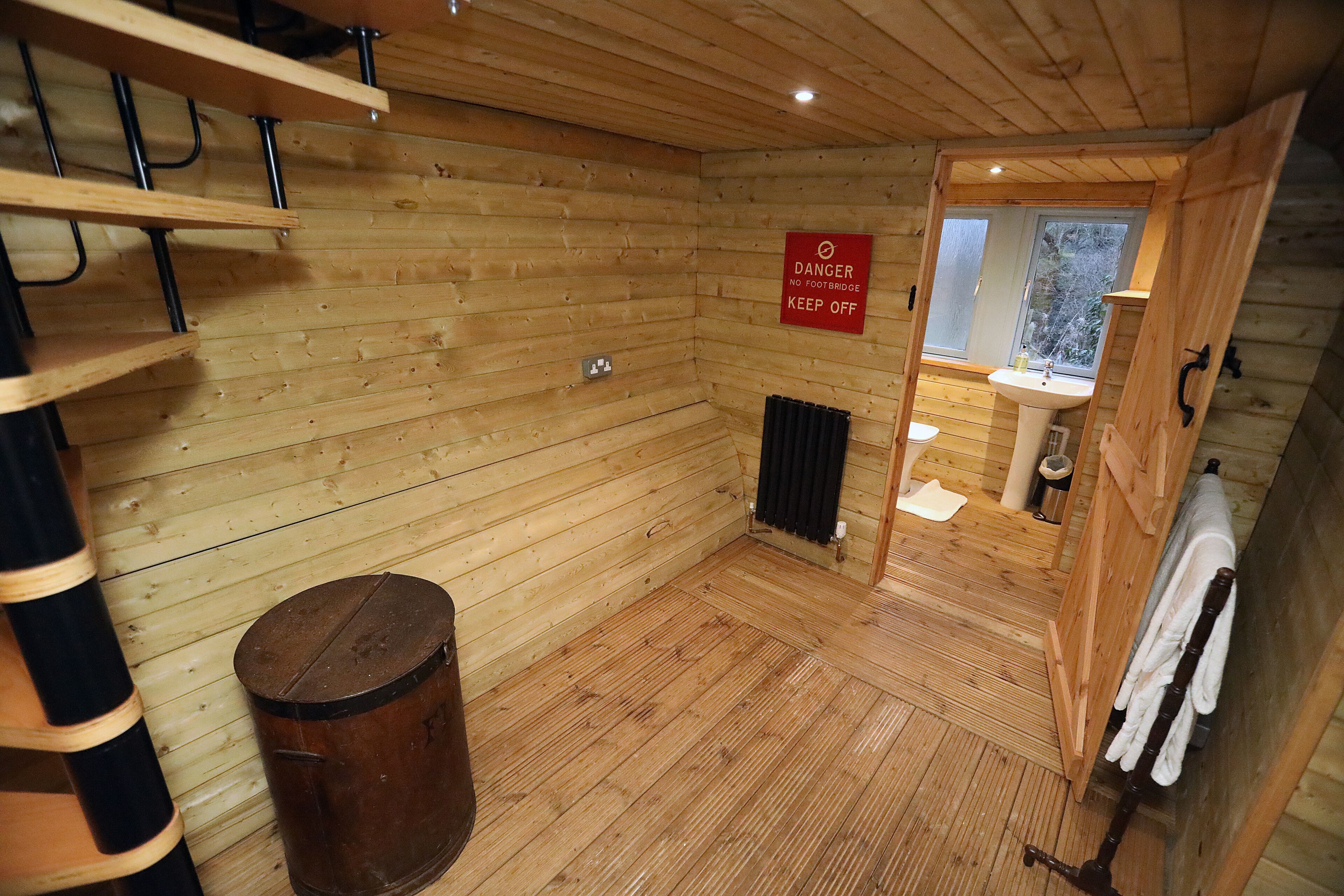 A wooden cabin bathroom with a shower, a sink, and a toilet.