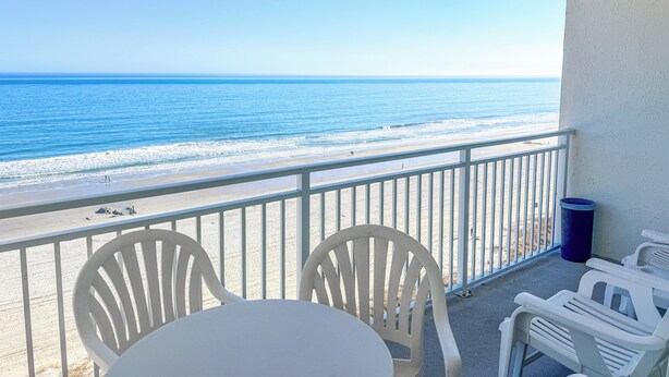 A balcony with a view of the beach and ocean.