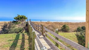 A wooden boardwalk leading to a beach with a clear view of the ocean.
