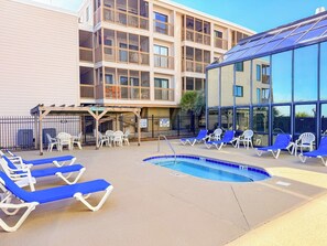 A pool area with lounge chairs and a building with multiple balconies in the background.