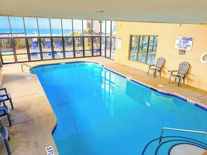 Una piscina interior con vistas despejadas al océano, un cartel de salvavidas y un letrero de prohibido fumar.