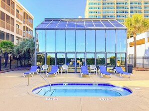 Una piscina con sillas de descanso y un edificio con paredes de vidrio.