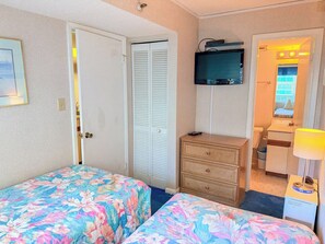 Habitación de hotel con dos camas, un aparador, televisor y baño visible a través de una puerta abierta.