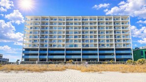 A multi-story hotel with a uniform exterior, multiple balconies, and a parking garage below.