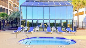 A swimming pool area with lounge chairs and a glass building in the background.