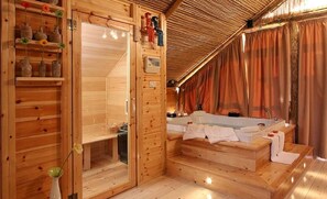 A wooden cabin with a sauna, a wooden bench, and a glass door.