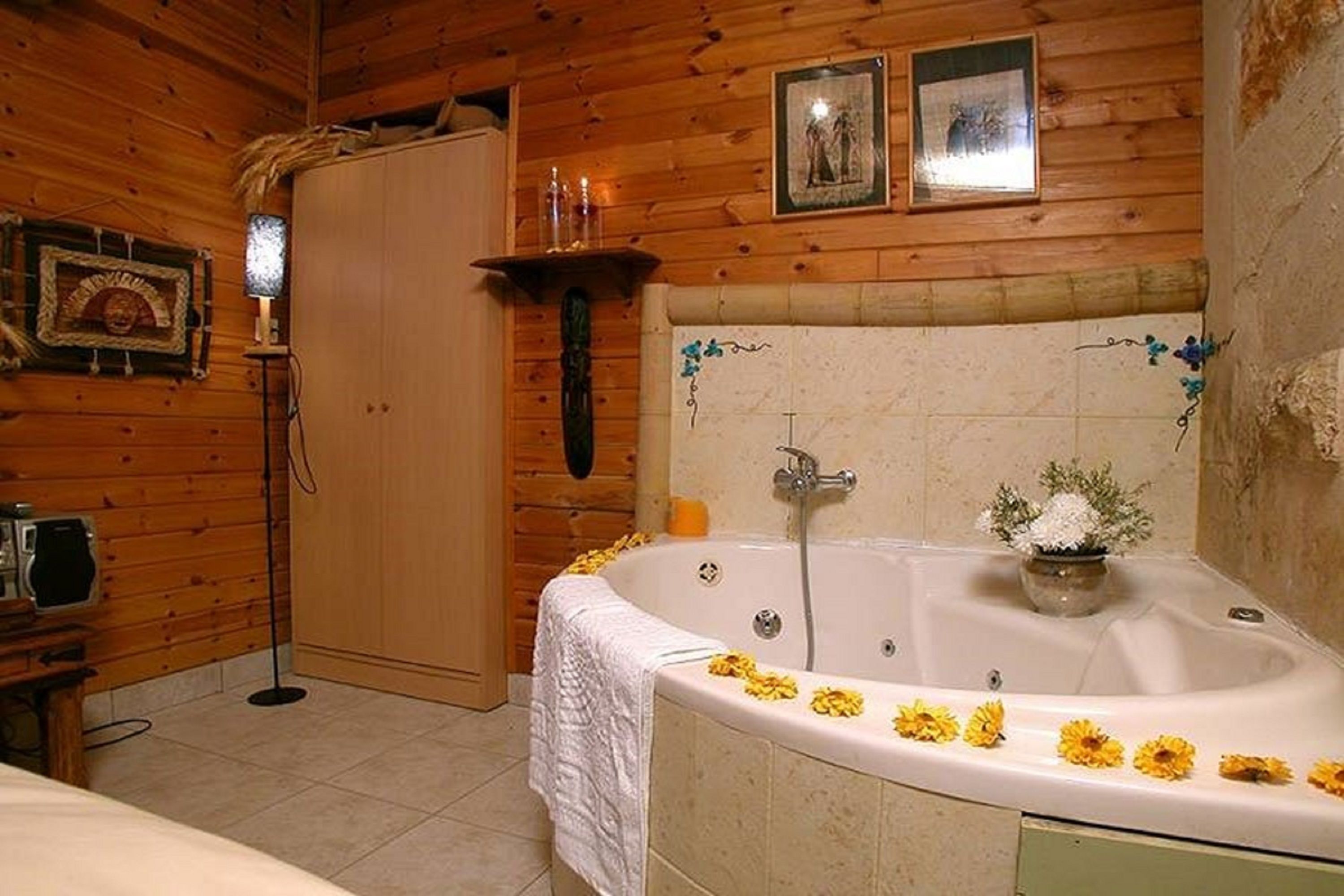 A wooden cabin bathroom with a bathtub, wooden walls, a wooden door, and a small shelf with bottles.