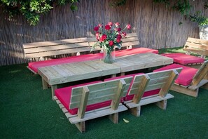 A wooden outdoor dining set with benches and a table, surrounded by a wooden fence and green grass.