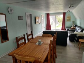 Ein Essbereich mit Holztisch und -stühlen, einer schwarzen Couch und einem Fenster mit Vorhängen.