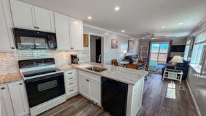 A modern kitchen with white cabinetry, a built-in oven, and a large island with a sink. - Inlet Point Villas #2A! Relax & Recharge in Cherry Grove’s Most Peaceful Corner (North Myrtle Beach)