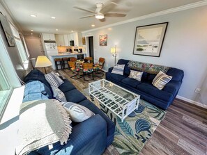 A living room with a sofa set, a coffee table, and a dining area with chairs. - Inlet Point Villas 2A (North Myrtle Beach)