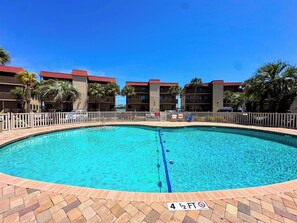 A circular pool with a clear blue water surface, surrounded by a brick deck and a white fence. - Inlet Point Villas 2A (North Myrtle Beach)