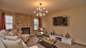A living room with a fireplace, a sofa, a coffee table, and a TV mounted on the wall.
