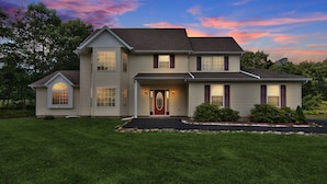 A two-story house with a front porch, a satellite dish, and a well-maintained lawn.