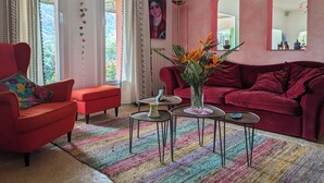 A living room with a red sofa, a red armchair, a colorful rug, and a vase with flowers. - rent large family villa near the sea and nature (Roquebrune-Sur-Argens)