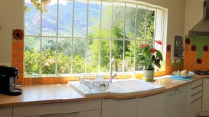 A kitchen with a large window, a coffee maker, a sink, and a fan. - rent large family villa near the sea and nature (Roquebrune-Sur-Argens)