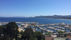 Un port de plaisance où de nombreux bateaux sont amarrés, entouré de collines et surplombé par un ciel bleu azur.