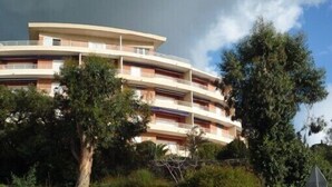 Un immeuble à plusieurs étages, doté de balcons et entouré d’arbres.