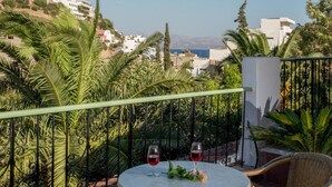 Una terraza con una mesa redonda, dos copas de vino tinto y mobiliario de mimbre.