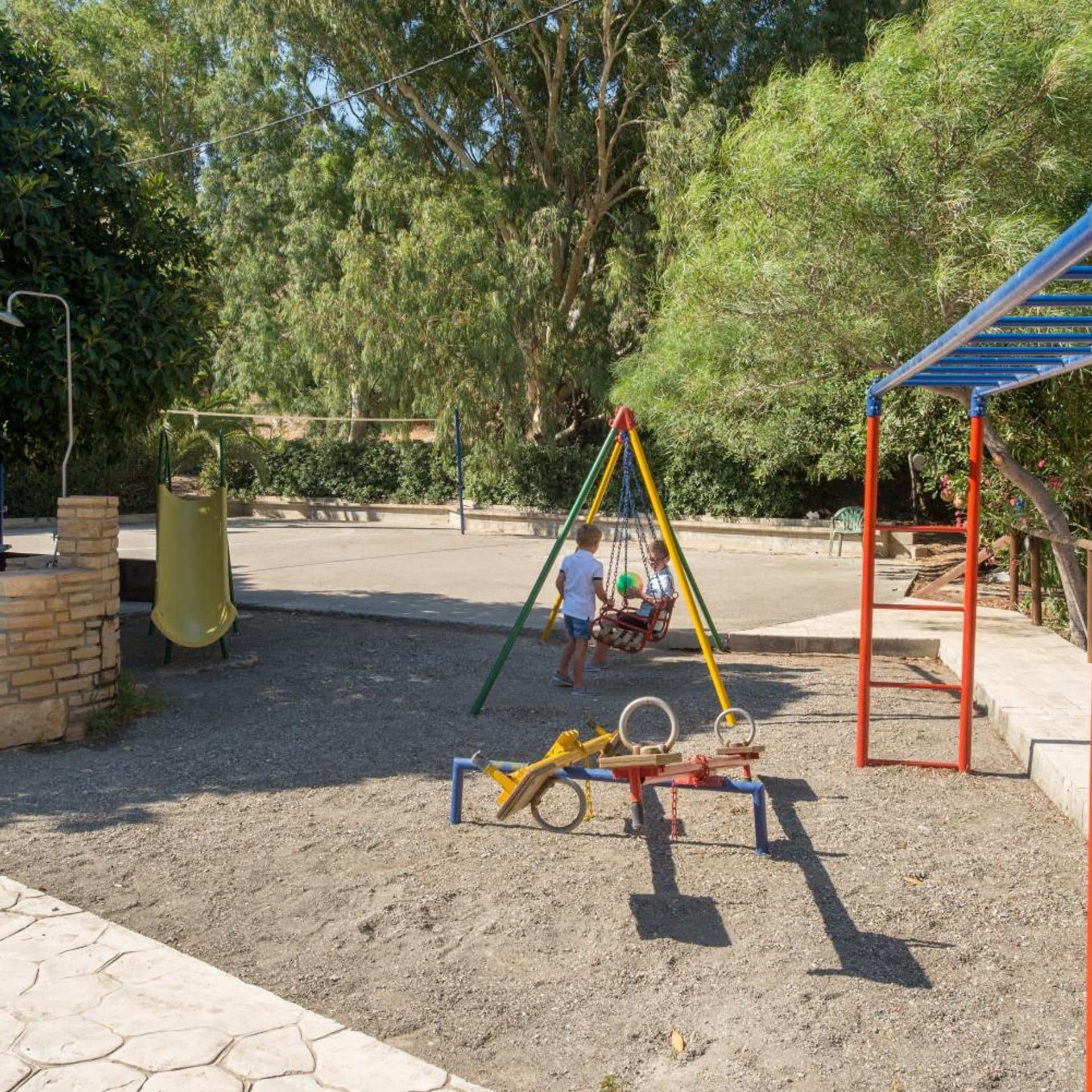 A playground with swings, a slide, and a seesaw.
