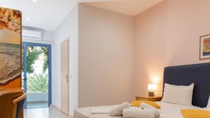 Un dormitorio con una cama, mesitas de noche, una silla y una puerta que da a un balcón.