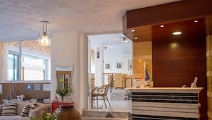 Un hall de hotel con mostrador de recepción, zona de estar con sofás y vista al interior.