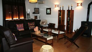Un saló amb un sofà, cadires, una taula de centre, una llar de foc i llums penjades a la paret.