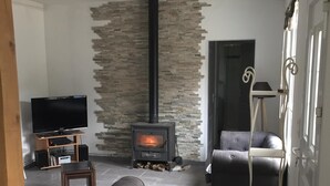 A living room with a stone wall, a fireplace, a television, a sofa, and a table.