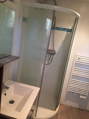 Een bad/douchecombinatie, handdoeken, toiletpapier