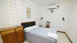 Ein Schlafzimmer mit Bett, Holzschrank, Wandklimaanlage und dekorativen Wandverkleidungen.
