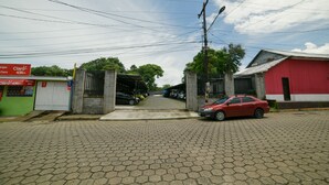 Eine gepflasterte Straße mit einem roten Auto, das rechts geparkt ist. Es sind Gebäude mit Schildern zu sehen, darunter eines mit der Aufschrift 'Claro 4.5G'.
