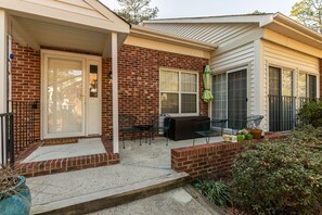 A house with a brick exterior, a front porch with a bench, and a patio area with outdoor furniture.