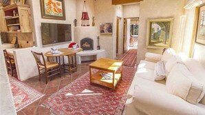 A cozy living room with a fireplace, a dining area with chairs and a table, and a sofa. - Luxury Guesthouse w Views, Private Sauna & Hot Tub- 30 day minimum. (Santa Fe)