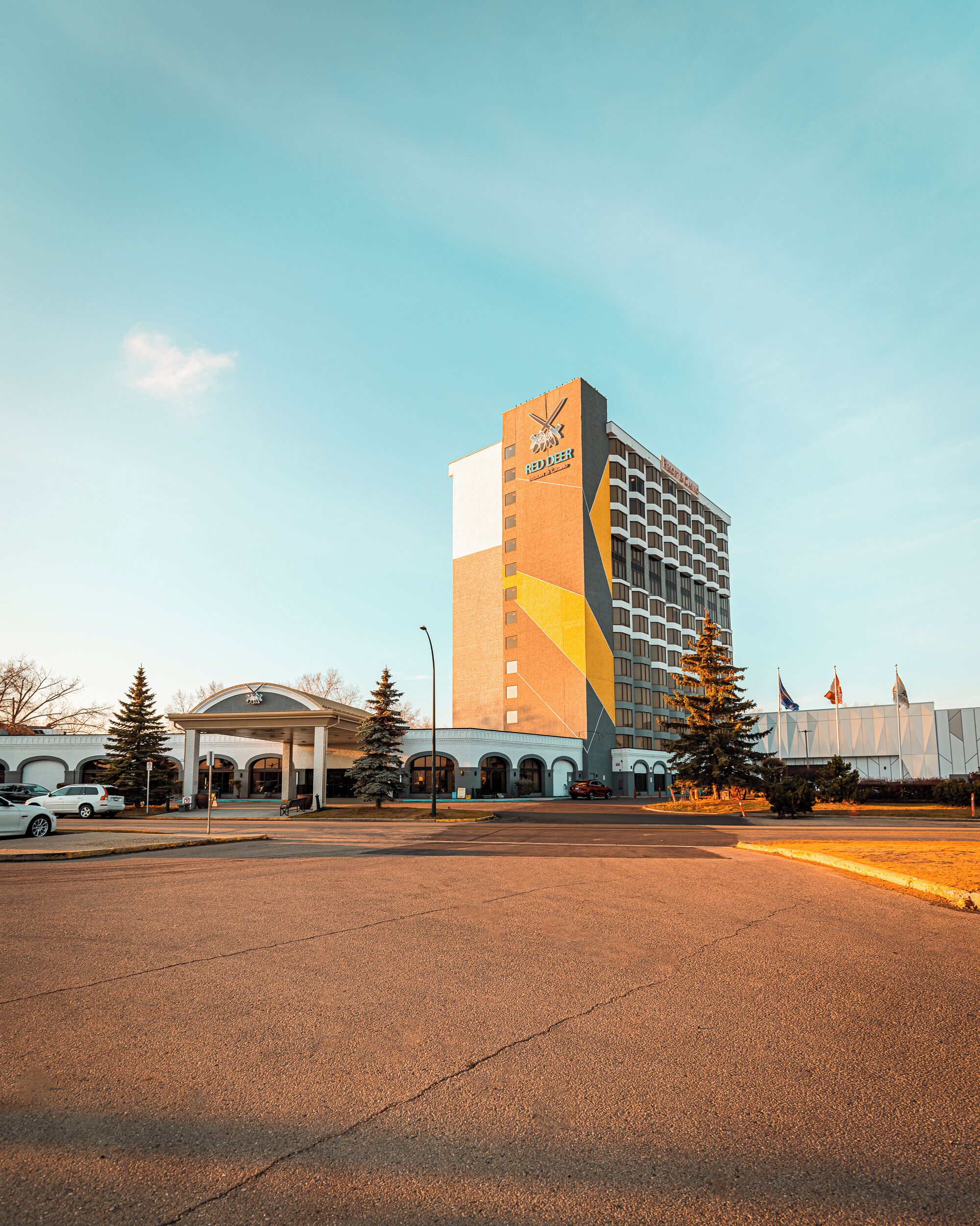 A hotel with a distinctive geometric facade, a covered entrance, and a parking lot.