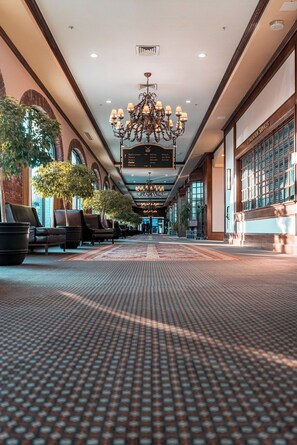 A spacious lobby with a patterned floor, leather seating, a chandelier, and a sign indicating 'Conference Services'.